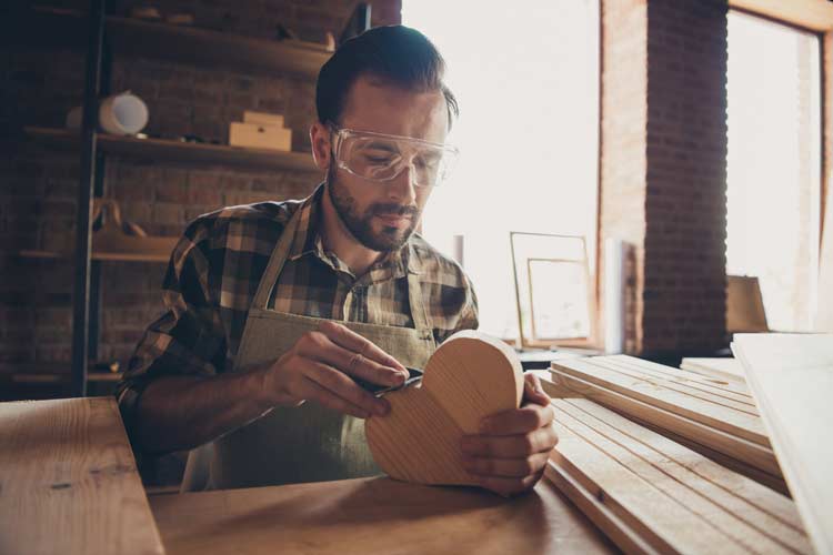 Partnerschaft retten: Ein Handwerker arbeitet an einem Herz aus Holz